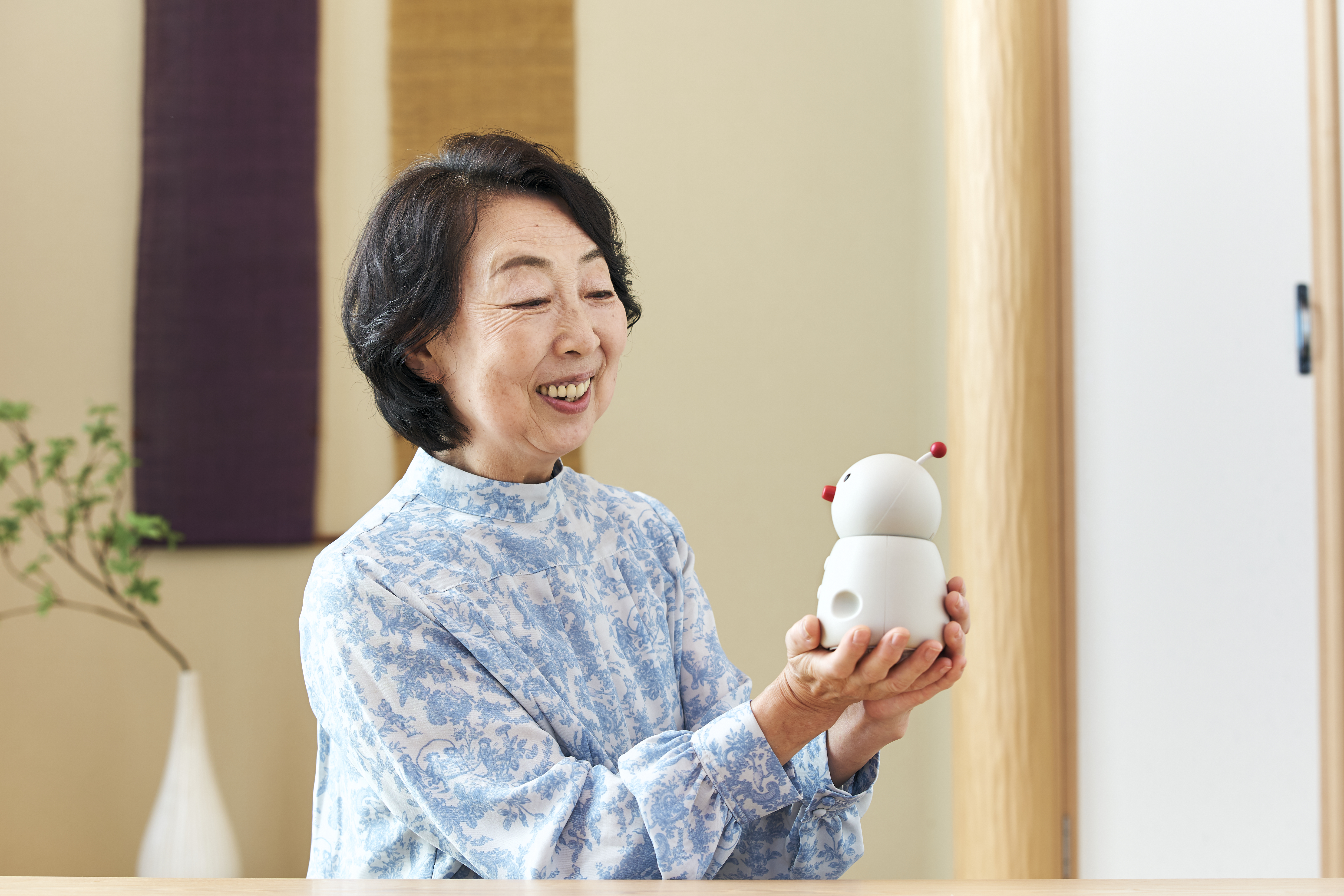 BOCCO emo communication robot by Yukai Engineering in a home setting, illustrating Japanese AgeTech for senior monitoring and family connectivity.